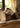 A collection of handwoven throw pillows with an accent of the dark-coloured lumbar pillow. It is placed on top of an antique wooden bed and styled with a white linen bedding.