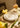 A dining table set up with white plates and farmhouse cutleries on top of a textured tablecloth with a golden tone. The table is fully decorated with yellow shades paper-flowers.