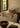A humble living room set with earthy-tone pillows made out of jute and silk. The place is furnished with white sofas and contrasting wooden antiques.